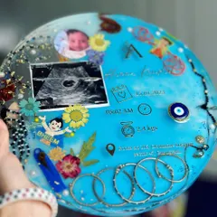 A closer look at the details in this 11-inch circular baby keepsake. You can see the sonogram, baby photo, birth stats, and other personal mementos like rakhis and silver kadas.