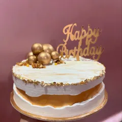 My popular almond butterscotch cake, shown here with a rustic white frosting and a caramel layer peeking through. It's topped with golden spheres and crunchy walnuts for texture and flavor.