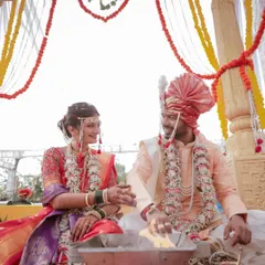 A candid moment during a Maharashtrian wedding ceremony. The bride and groom share a smile, seated at the holy fire, their connection evident even during the rituals.