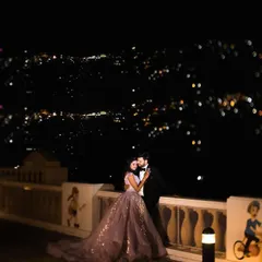 A romantic night portrait of a couple in Mussoorie, with the sparkling city lights creating a magical bokeh effect. We specialize in using creative lighting for stunning night shoots.