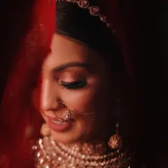 A classic bridal portrait, using the red veil to create a soft, intimate frame. This signature shot focuses on the bride's serene expression and detailed makeup.