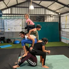 Teamwork makes everything better. Here, my students are working together to build a five-person human pyramid. This kind of partner acrobatics builds strength, balance, and trust between the kids.