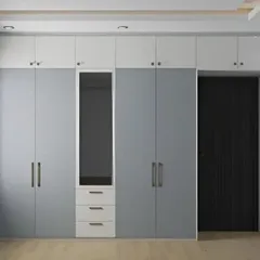 This floor-to-ceiling wardrobe in a calming grey and white palette offers immense storage. The design includes a built-in dressing mirror, making it a highly functional addition to the bedroom.