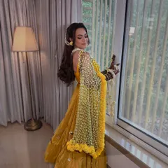 A radiant Haldi bride posing by the window. Her look is completed by my signature Tagar bud floral dupatta and matching jewellery.