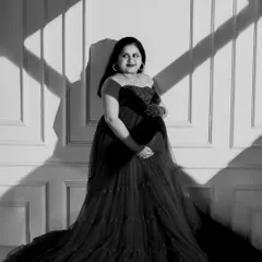 A striking black and white portrait using strong directional light. The play of light and shadow across the wall and the mom-to-be creates a bold, graphic, and artistic image.