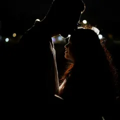 A dramatic silhouette portrait of the couple against the dark night, with a gentle forehead kiss. This technique creates a feeling of intimacy and romance.