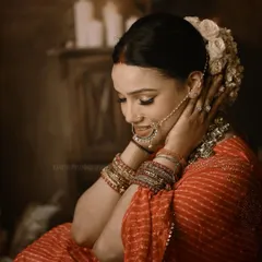 A dramatic bridal portrait using low-key lighting to create a moody and timeless feel. The focus is on the bride's quiet elegance, traditional jewelry, and the rich textures of her attire in a studio setting.