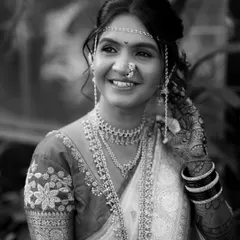 A timeless black and white bridal portrait. This image highlights the bride's joyful expression and the delicate details of her jewelry and embroidered blouse, creating a classic and elegant feel.