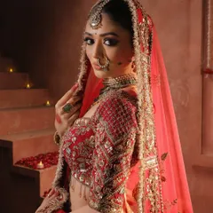 A close-up of this queenly bride, framed by her red dupatta. Her makeup features dramatic winged eyeliner, rich eyeshadow, and perfectly defined brows, creating a powerful and mesmerizing gaze.