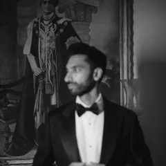 A moody, black and white portrait of Sid in his tuxedo. The painting in the background adds a sense of history and grandeur to this reception look.