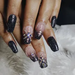 A truly glamorous set of square-shaped extensions combining black glitter polish with intricate, multi-colored 3D rhinestone designs for maximum sparkle and impact.