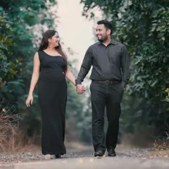 A candid moment of a couple walking hand-in-hand through a tree-lined path. Outdoor sessions allow for natural movement and interaction, resulting in relaxed and authentic photos.