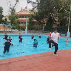 I lead the class from the side of the pool, demonstrating the next move for our aqua aerobics session.