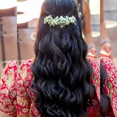 Soft, romantic waves are a popular choice. Here, they are styled into a simple half-updo and adorned with a delicate baby's breath accessory.