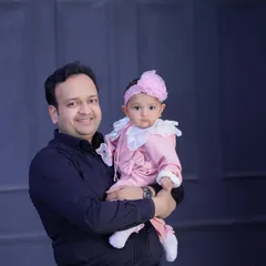 A proud father holds his baby girl, who is looking curiously at the camera. A simple and sweet father-daughter portrait.