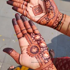The beauty of a fresh henna stain. This design shows a mix of styles, with a geometric pattern on one hand and a floral mandala on the other, both featuring lotus motifs.