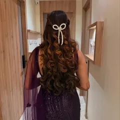 A close-up of this super trendy pearl bow hair accessory. It's a simple touch that makes a big statement in this curly half-up hairstyle.