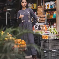A campaign for a sustainable fashion brand, shot on location at a local market. The embroidered grey dress blends beautifully with the rustic, everyday environment.