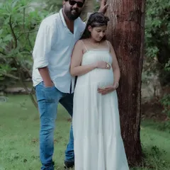 This classic couple maternity pose highlights the connection between the partners and their unborn child in a serene, green environment.