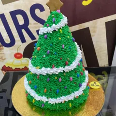 A festive 3kg cake sculpted into a Christmas tree with green piping and colorful sprinkle ornaments.