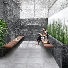 I designed this serene terrace lounge as a private retreat within a bustling city. The space features a perforated roof that creates a beautiful play of light and shadow, slate stone walls, and built-in wooden seating, embodying my love for biophilic design.