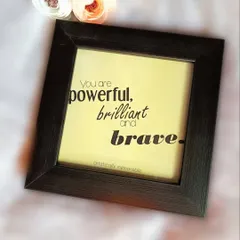 Another view of the "powerful, brilliant and brave" quote frame, styled with small flowers to highlight its aesthetic appeal as desk or wall decor.