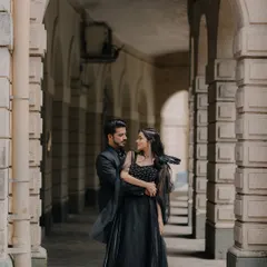 A candid moment of the couple sharing a look within an architectural corridor. The play of light and shadow adds to the romantic, story-like feel of the photograph.