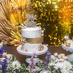 The 50th birthday cake setup against a glamorous gold sequin backdrop, creating a luxurious and celebratory atmosphere.