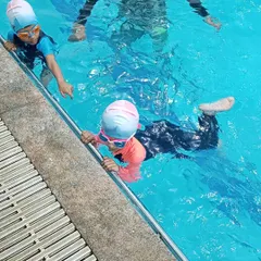 Young learners practicing their kicks along the side of the pool, a fundamental drill in our kids' swimming classes.