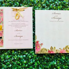 This floral wedding invitation combines a laser-cut panel with a delicate ribbon tie. The pink and gold color palette is both romantic and elegant, with a custom gold foil monogram adding a personal touch.