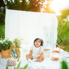 This little one is looking up with such a sweet expression during her outdoor birthday picnic photoshoot. The golden light is just magical.