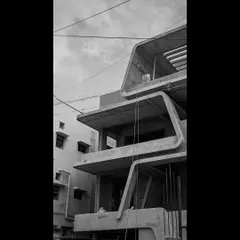 The raw concrete form of a building in progress, showcasing the bold, angular lines and cantilevered balconies that define its architectural character.