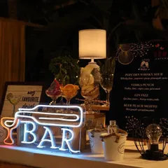 It's all in the details. This close-up shows our custom neon signage and a bespoke cocktail menu featuring creative drinks like the 'Popcorn Whisky Sour'. We work with you to design every element to fit your unique theme and taste.