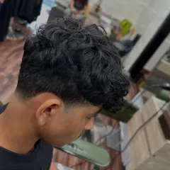 A side profile of a perfectly executed taper fade on curly hair. Learning to work with different hair textures is a key part of our advanced barbering curriculum.
