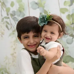 A sweet and simple portrait of a brother and his baby sister. The light, leafy background and their happy expressions make for a timeless image that celebrates their sibling bond.
