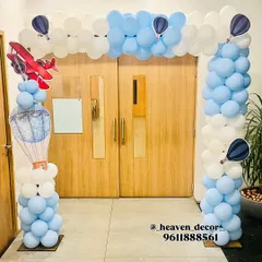An impressive entrance arch for an airplane-themed party. The doorway is framed with blue and white balloons resembling clouds, with airplane and hot air balloon cutouts.