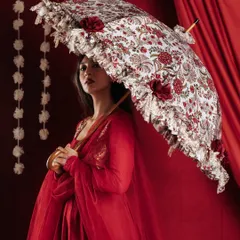 Here, the composition uses the ornate umbrella to frame the model's face, drawing the viewer's eye to both the product and the mood. The soft lighting enhances the texture of the fabric and the intricate floral patterns on the umbrella.