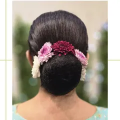 A timeless and elegant floral bun. This sleek, perfectly crafted updo is adorned with fresh flowers, making it ideal for weddings and traditional events.