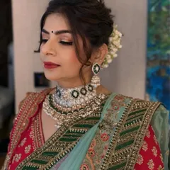 A bride with her eyes gently closed, showcasing the flawless bridal makeup. We focused on a soft glam eye with a classic red lip, complemented by a voluminous updo adorned with fresh gajra for a traditional yet polished look.