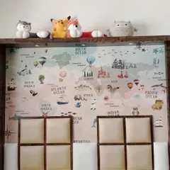 For this kid's bed, I installed a world map wallpaper and a custom padded headboard. The headboard features four soft, upholstered squares within a wooden frame for comfort and style.