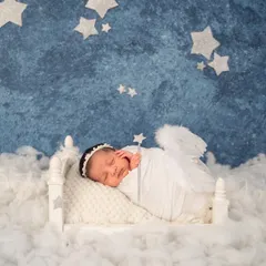 A little angel sleeping on a bed of clouds. This dreamy setup uses a starry backdrop, fluffy clouds, and delicate angel wings to create a truly magical portrait.