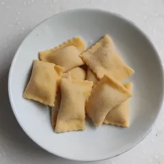 Freshly made ravioli, dusted with flour and ready to be cooked. We teach the art of making various stuffed pastas.