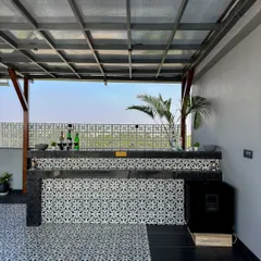 This bar combines modern and classic elements, with a patterned tile front and a sleek black countertop. It's a functional and stylish addition to this covered terrace lounge.