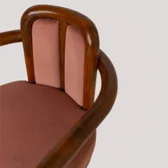 The 'Svelte' dining chair, an experimental piece made of bent teakwood. The dark mauve, feather-touch fabric and brass leg caps give it an ultra-sophisticated and poised appearance, making it the perfect companion for a statement table.