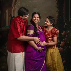 A heartwarming family portrait from a traditional Indian session. The genuine smiles and loving interactions between the parents and their daughter beautifully capture the joy of welcoming a new baby.