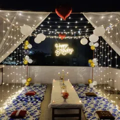 An elegant cabana dinner setup on a terrace, fully equipped with low seating, candles, and fairy lights for a magical birthday evening.
