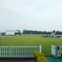 A wide view of the teams on the field during a competitive match. Our academy ensures players get the full experience of playing in large, well-maintained stadiums, preparing them for the pressures of professional cricket.