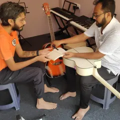 Guidance and growth. A moment of mentorship as knowledge is passed from teacher to student, helping with the finer points of guitar maintenance.