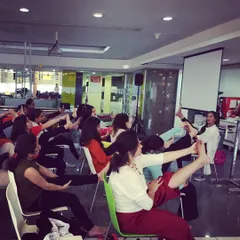 A seated leg stretch during a corporate yoga class. These simple exercises can be done right at your desk to improve circulation and prevent stiffness.