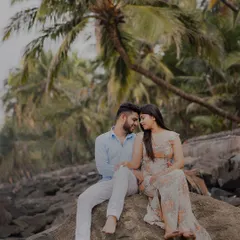 A quiet moment on a rocky shore, with palm trees framing the scene. This shot captures the peaceful, romantic essence of a beach pre-wedding shoot, away from the crowds.